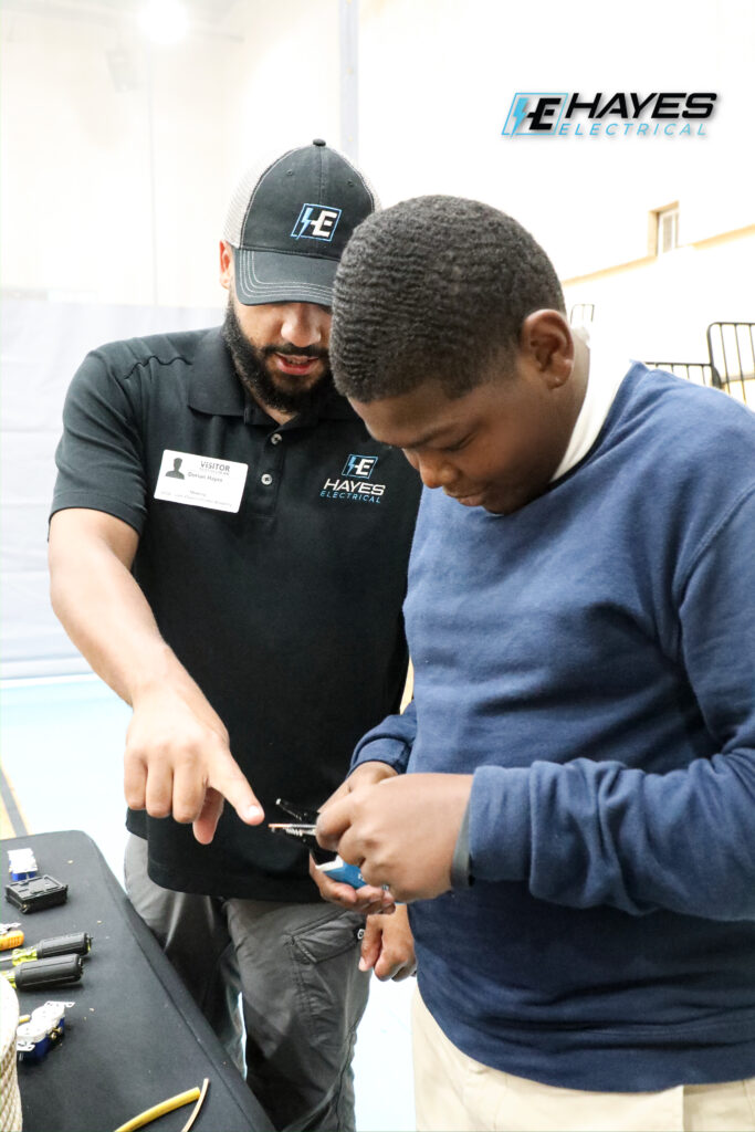 Our team member demonstrates basic electrical wiring skills to a student at a Lake Charles Charter Academy event.