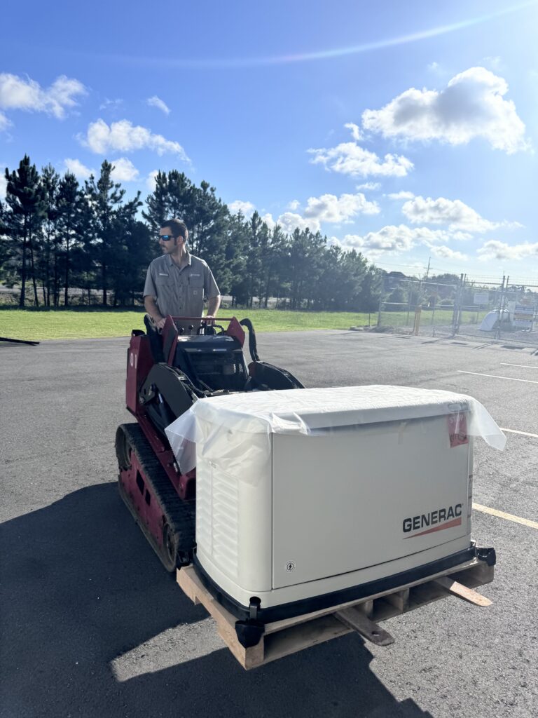 A Hayes Electrical team member expertly maneuvers a Generac generator into position using a mini skid steer.